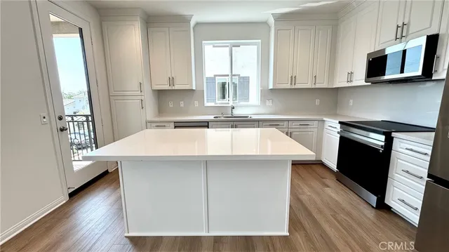 a kitchen with stainless steel appliances a stove a microwave and a hard wood floors