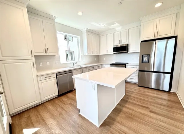 a kitchen with a refrigerator a sink and dishwasher with wooden floor