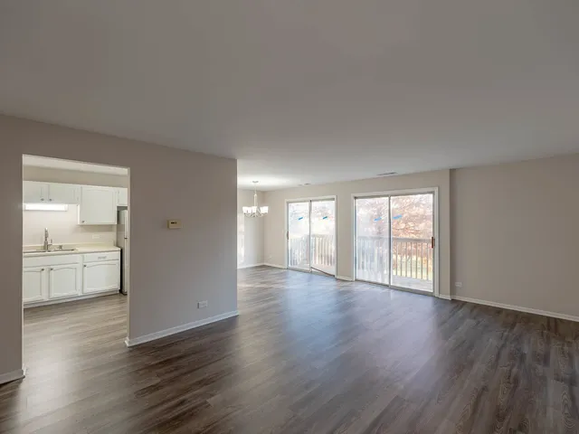 a view of an empty room with wooden floor and windows