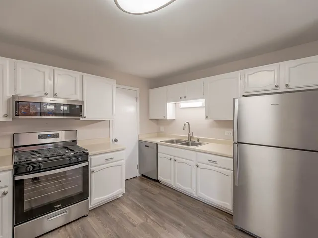 a kitchen with cabinets stainless steel appliances and wooden floor