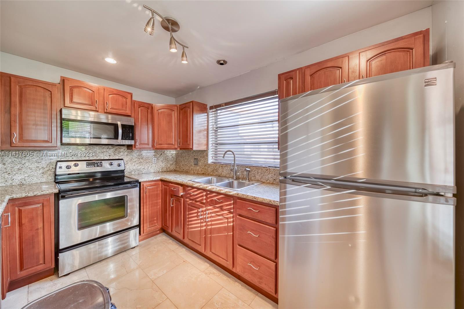 13440 Southwest 62nd Street, Unit G101 Miami, FL 33183 - Photo 11 of 25 a kitchen with stainless steel appliances granite countertop a stove a sink and a microwave