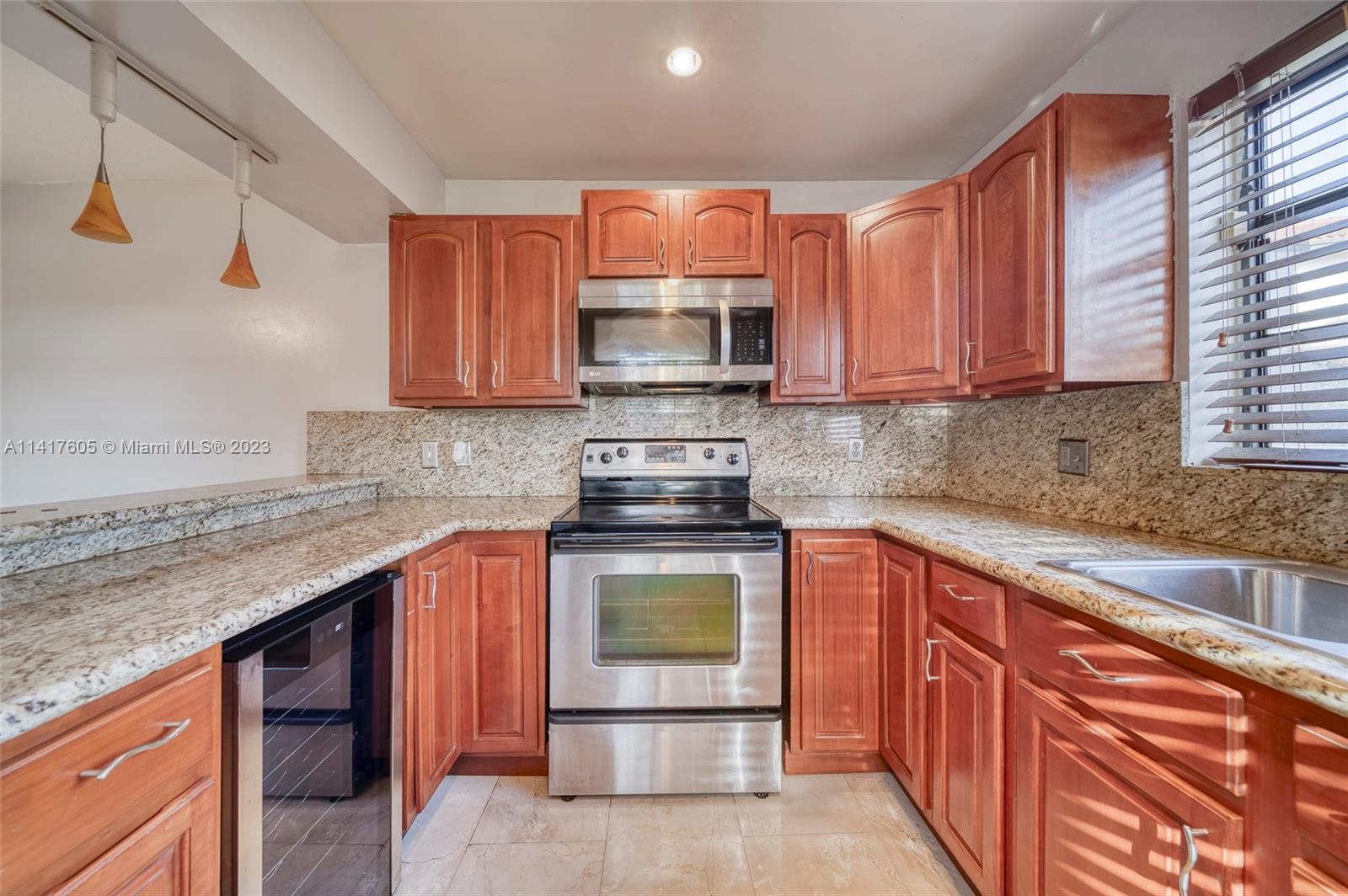 13440 Southwest 62nd Street, Unit G101 Miami, FL 33183 - Photo 13 of 25 a kitchen with granite countertop a stove top oven cabinetry a sink and a refrigerator