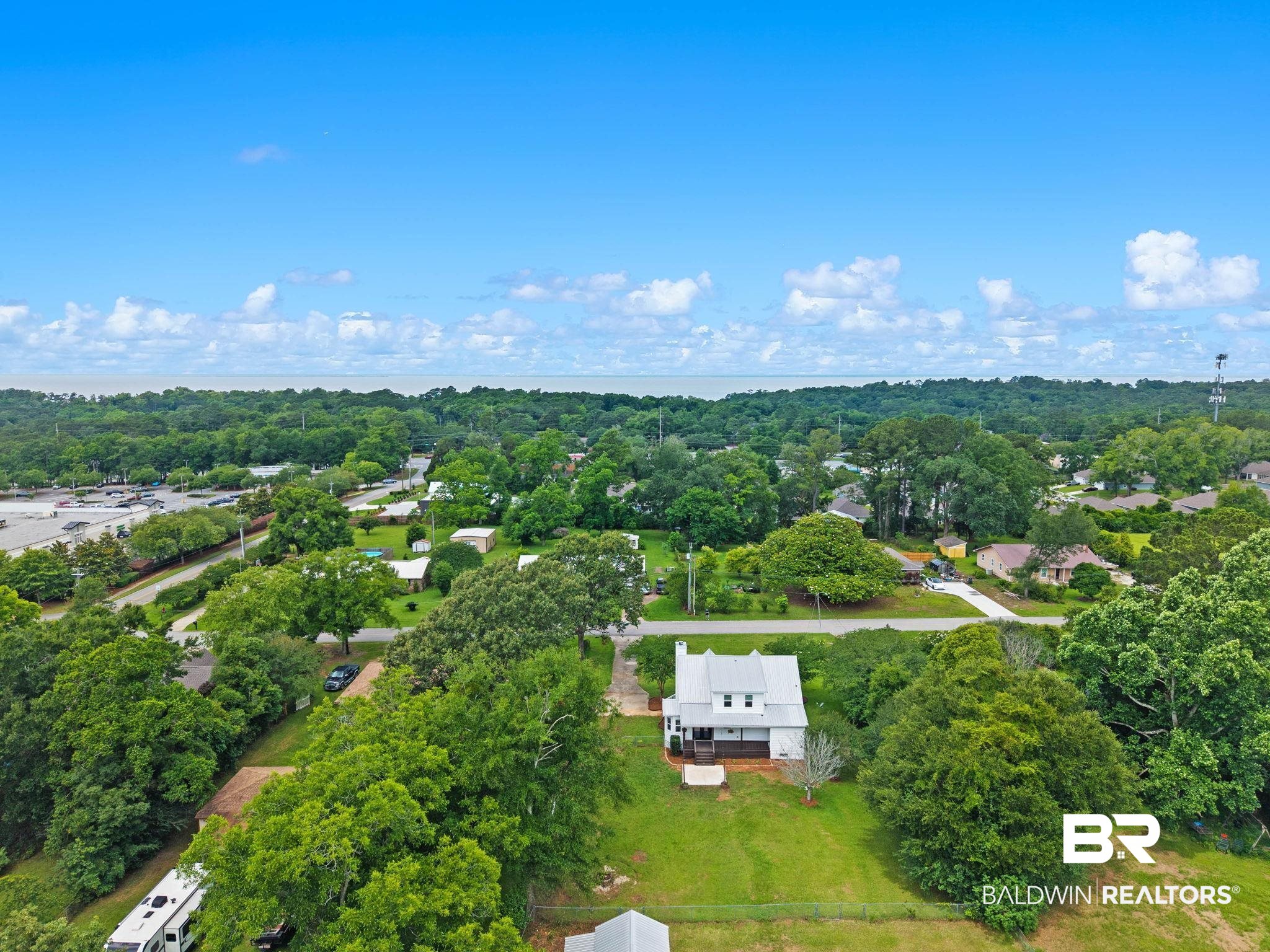 22810 High Ridge Road Fairhope, AL 36532 - Photo 69 of 78 White two-story residence with a metal roof and an expansive green lawn, surrounded by mature trees