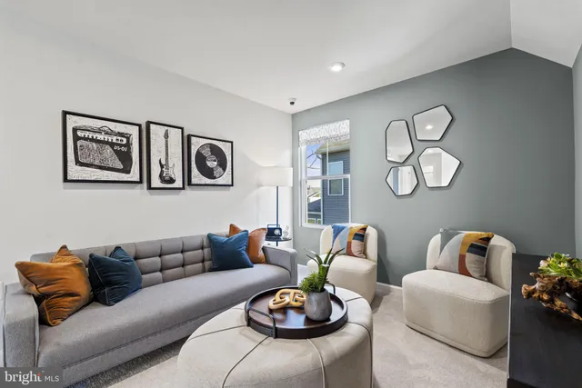 a living room with furniture a rug and wall paintings