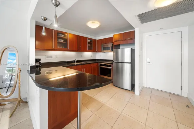 a kitchen with stainless steel appliances granite countertop a sink a refrigerator and a microwave