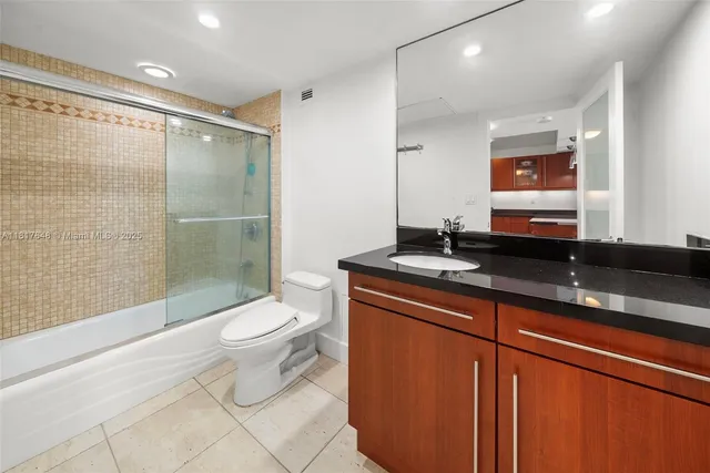 a bathroom with a granite countertop sink toilet and shower