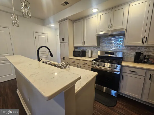 a kitchen with granite countertop a sink a stove and cabinets