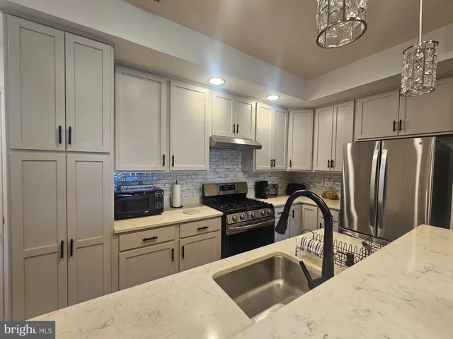 a kitchen with stainless steel appliances granite countertop a refrigerator sink and stove
