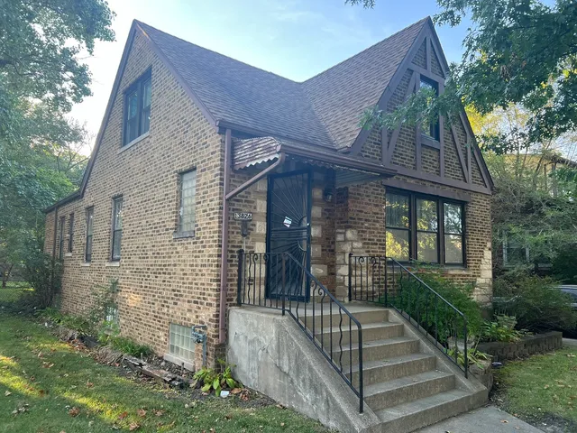 a view of brick house with large windows and a small yard