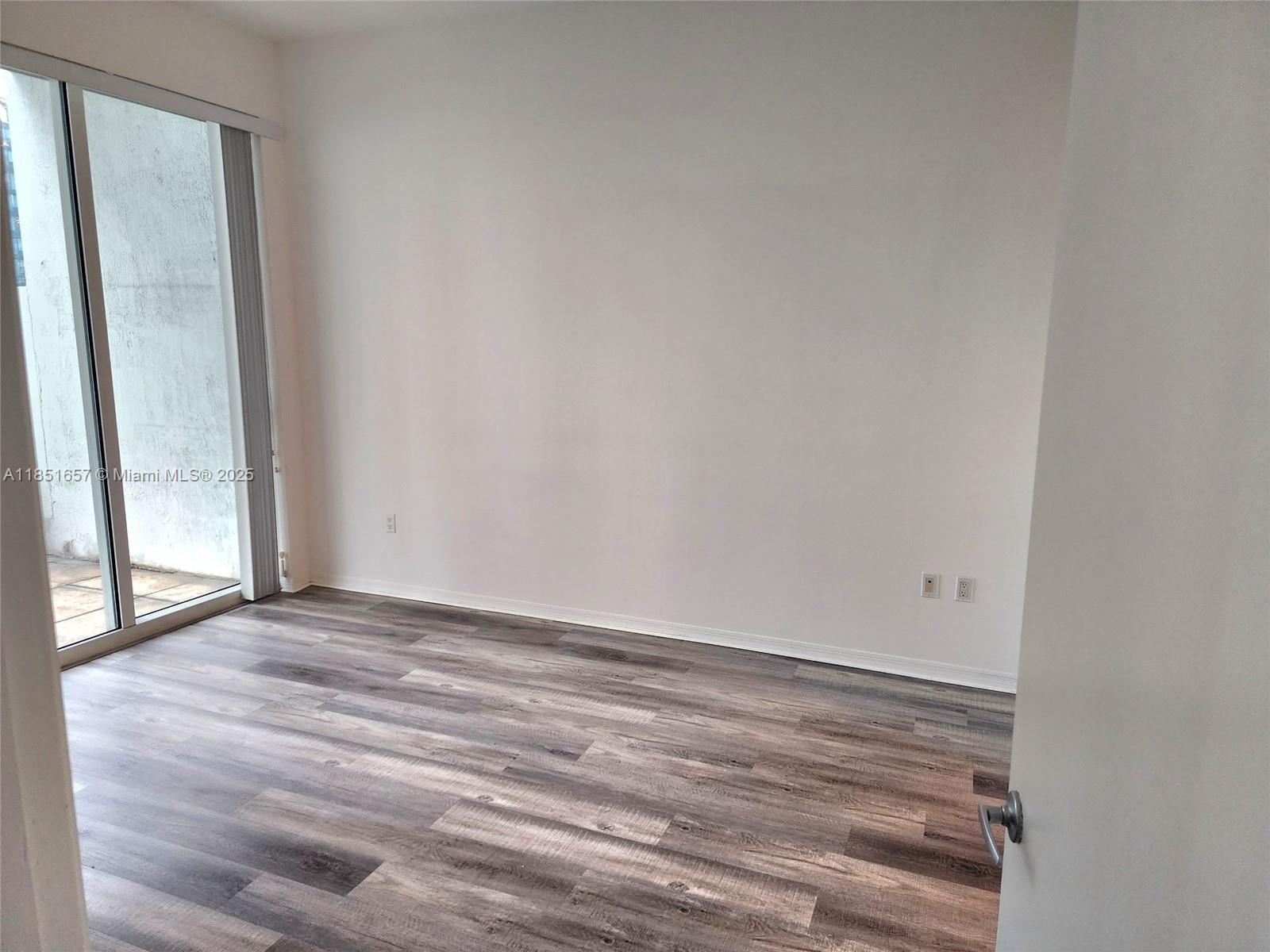 951 Brickell Avenue, Unit 1007 Miami, FL 33131 - Photo 18 of 25 a view of an empty room with wooden floor and a window