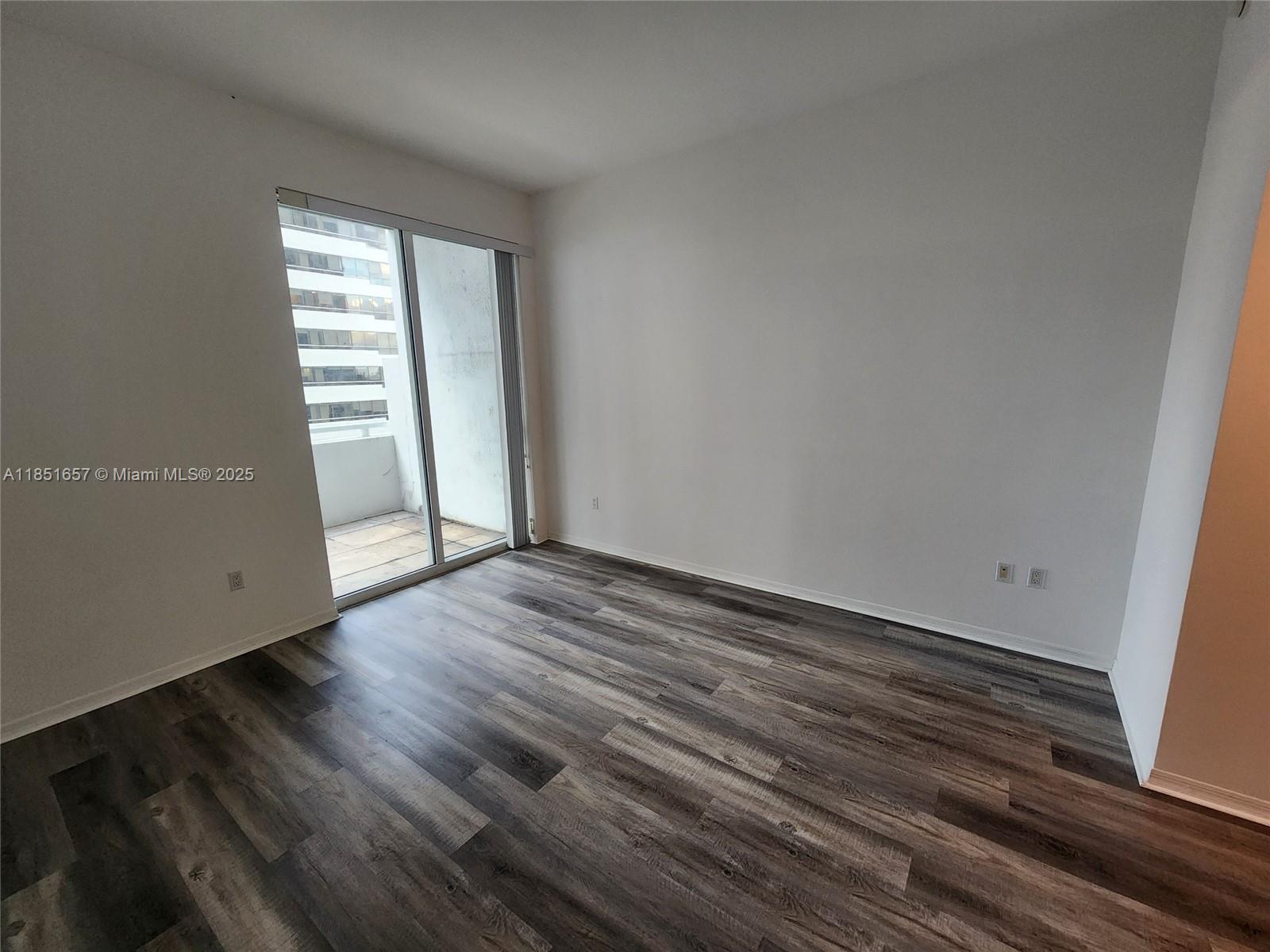 951 Brickell Avenue, Unit 1007 Miami, FL 33131 - Photo 19 of 25 a view of an empty room with wooden floor and a window