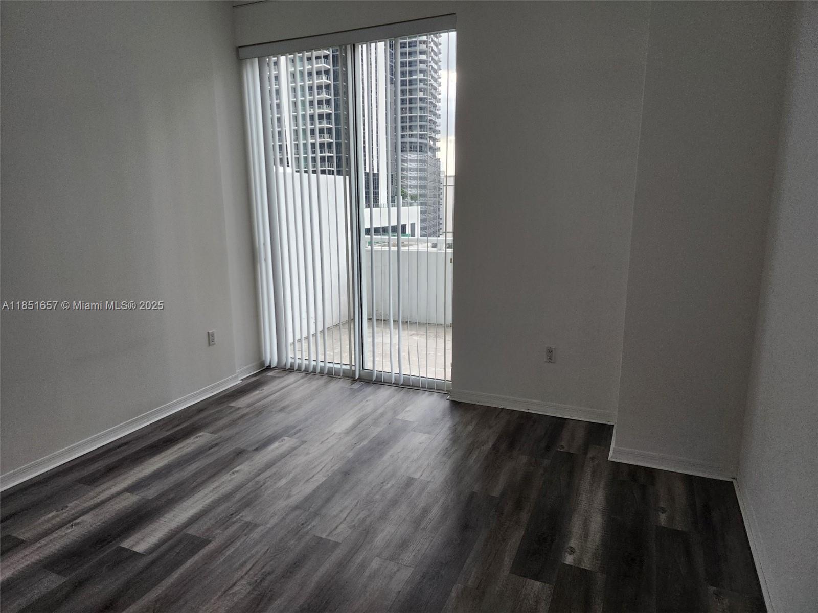 951 Brickell Avenue, Unit 1007 Miami, FL 33131 - Photo 22 of 25 an empty room with wooden floor and windows
