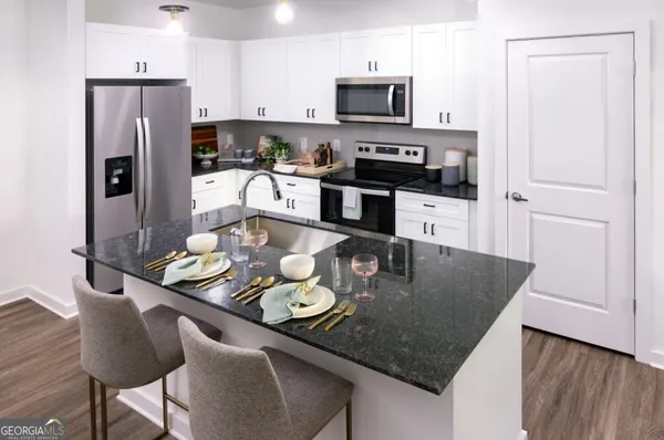 a kitchen with stainless steel appliances granite countertop a sink a stove a microwave a dining table and chairs