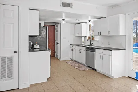 a kitchen with white cabinets and sink