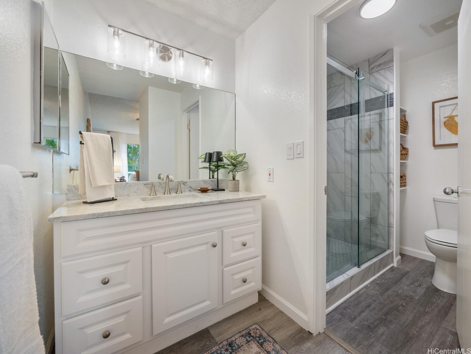 594 Mananai Place, Unit 21T Honolulu, HI 96818 - Photo 16 of 25 a bathroom with a granite countertop sink a toilet and shower