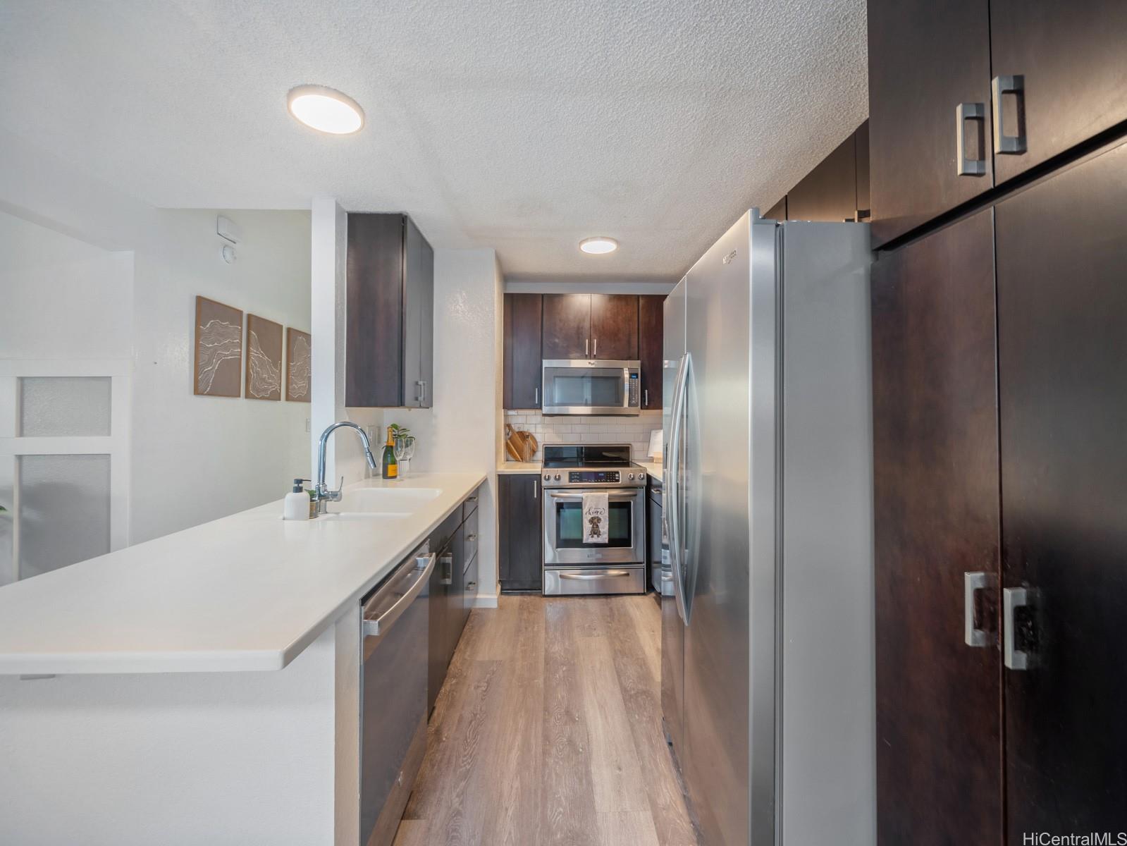 594 Mananai Place, Unit 21T Honolulu, HI 96818 - Photo 9 of 25 a kitchen with kitchen island a counter top space stainless steel appliances and cabinets