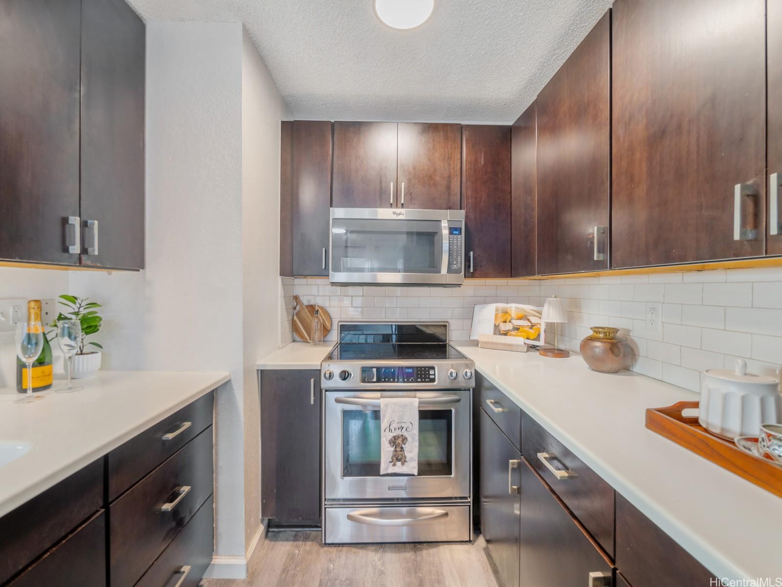 594 Mananai Place, Unit 21T Honolulu, HI 96818 - Photo 10 of 25 a kitchen with granite countertop stainless steel appliances a stove a sink a counter space and cabinets