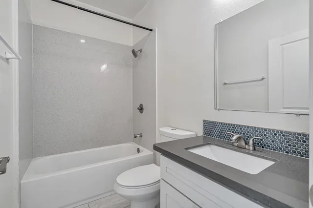 a bathroom with a granite countertop sink a toilet and a bathtub