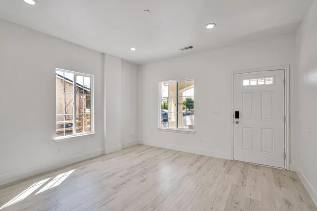 an empty room with wooden floor and windows