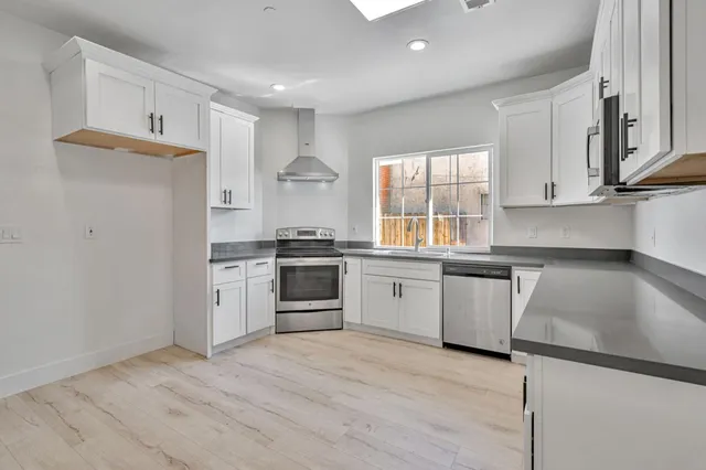 a kitchen with granite countertop white cabinets a sink a window and stainless steel appliances