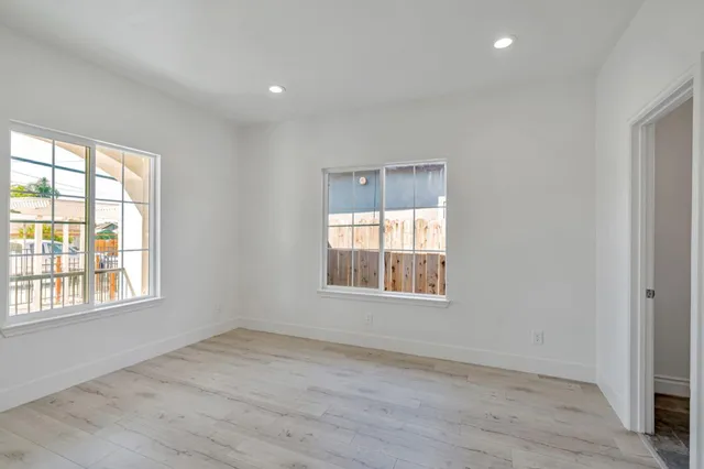 a view of an empty room with a window and wooden floor