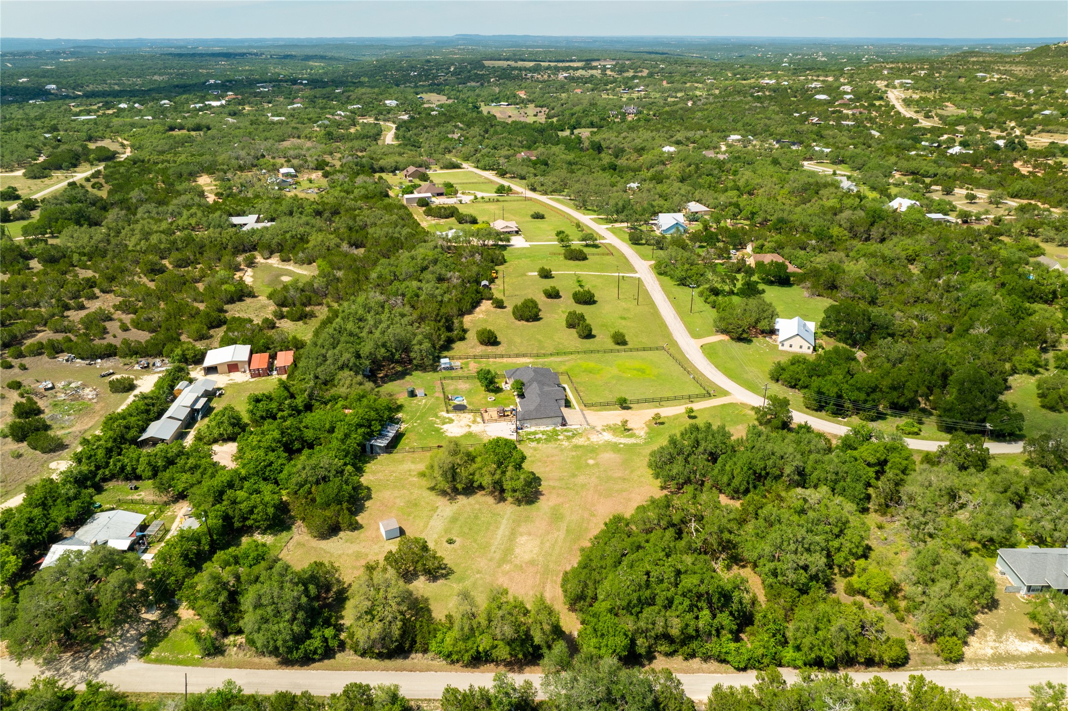 187 Beauchamp Road Dripping Springs, TX 78620 - Photo 14 of 19 Expansive property featuring a black-roofed residence, extensive green acreage, perimeter fencing, and mature trees
