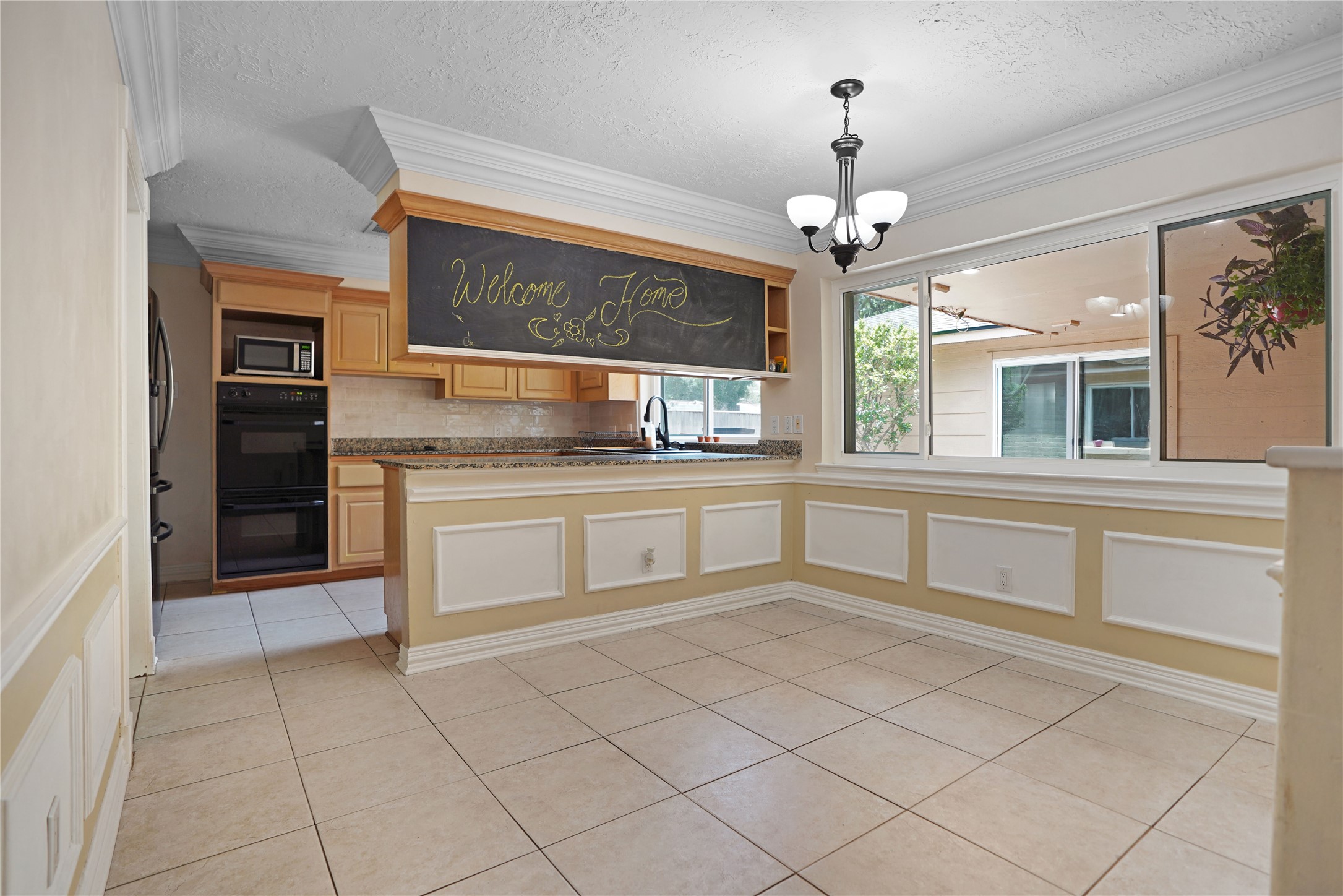 17119 Mellow Ridge Drive Spring, TX 77379 - Photo 7 of 32 This bright kitchen-dining area features tiled floors, a cozy breakfast bar with granite countertops, and ample natural light from large windows. A stylish chandelier and a welcoming chalkboard add charm to the space.