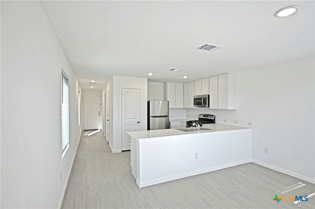 11806 Bluebell Ridge Converse, TX 78109 - Photo 7 of 20 a kitchen with stainless steel appliances a sink a stove a refrigerator and white cabinets