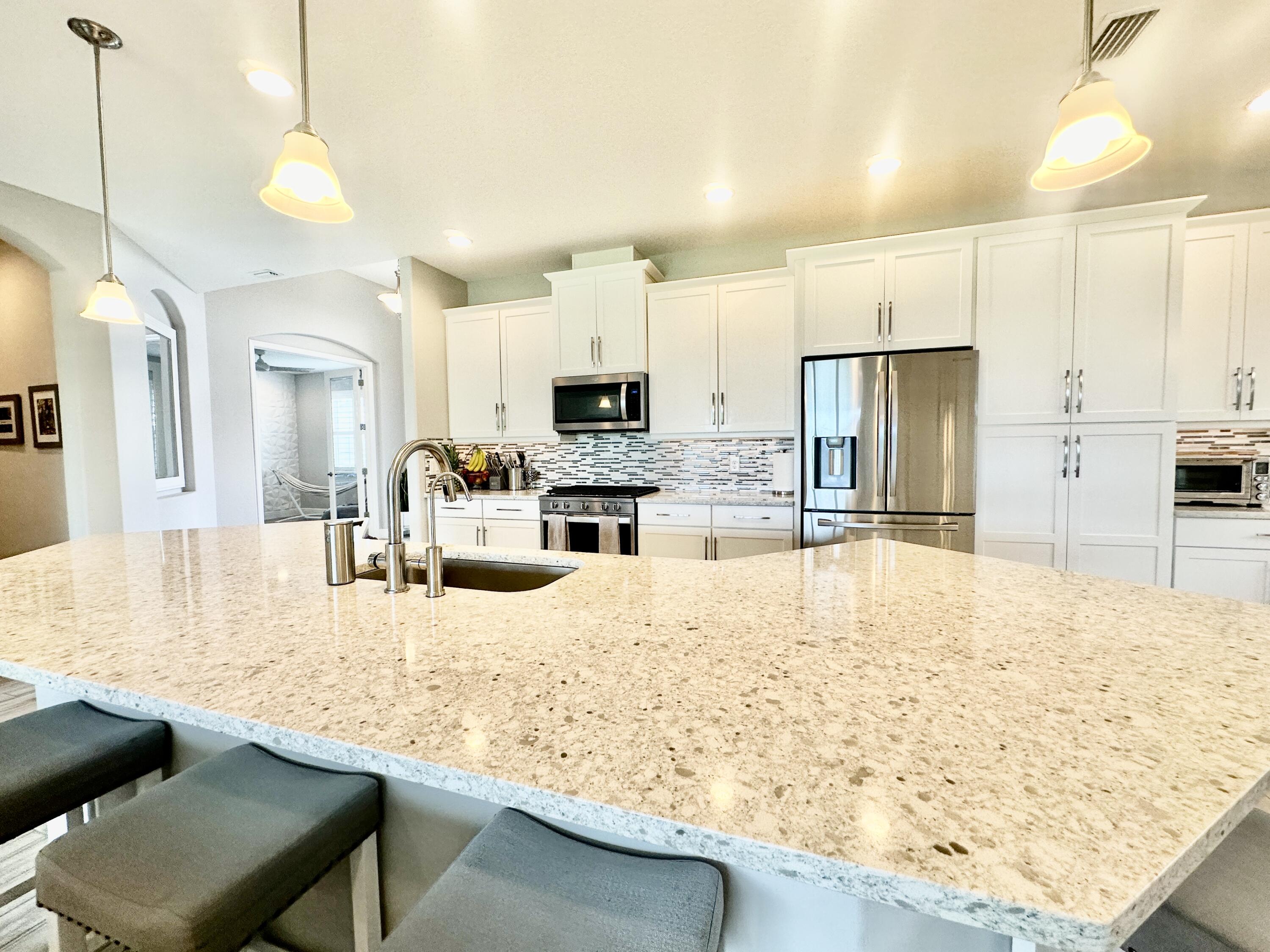 3044 Trasona Drive Melbourne, FL 32940 - Photo 11 of 36 a large kitchen with kitchen island a sink stove and white cabinets