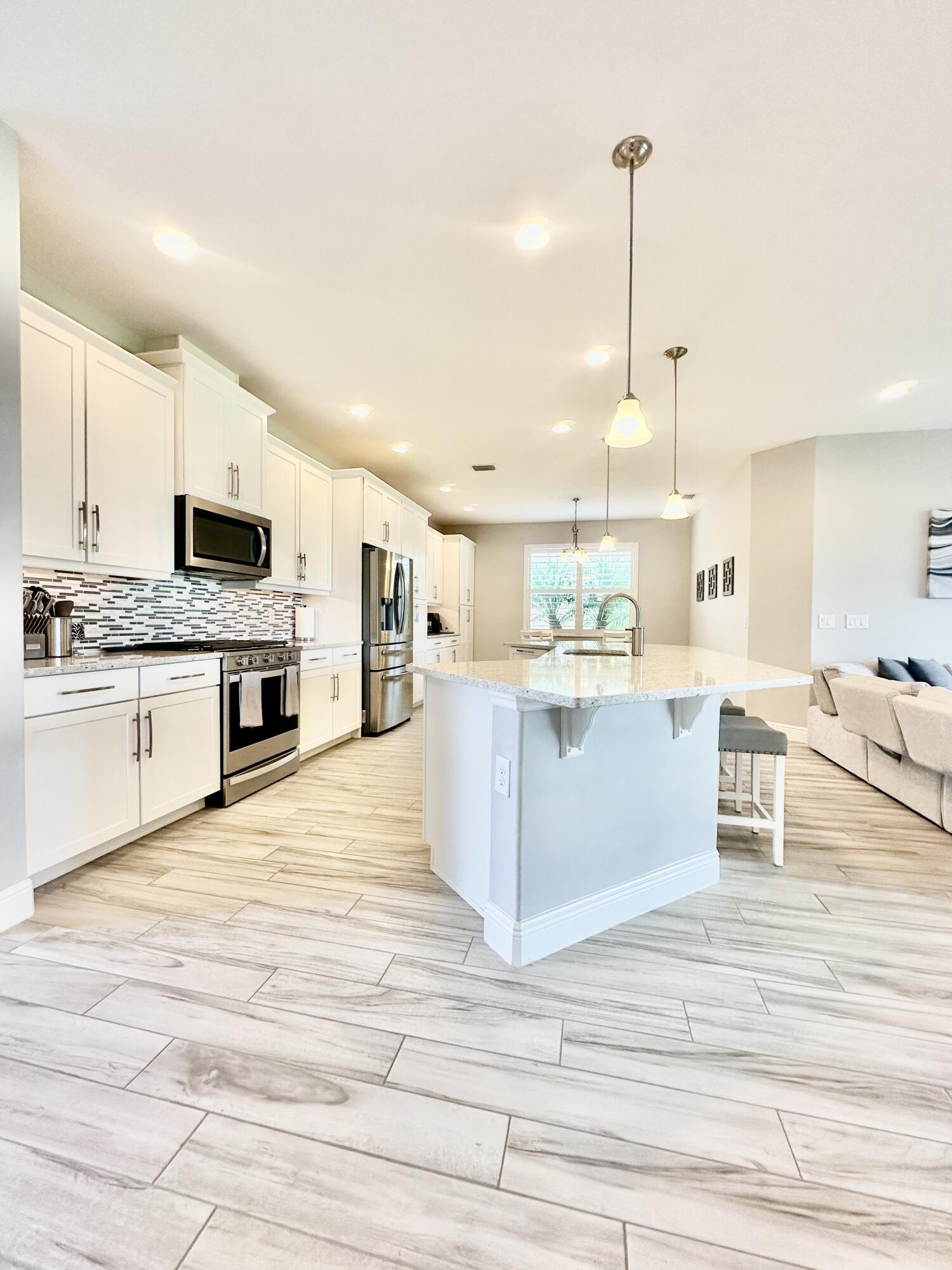 3044 Trasona Drive Melbourne, FL 32940 - Photo 6 of 36 a view of kitchen with kitchen island stainless steel appliances a stove a sink cabinets and a wooden floor