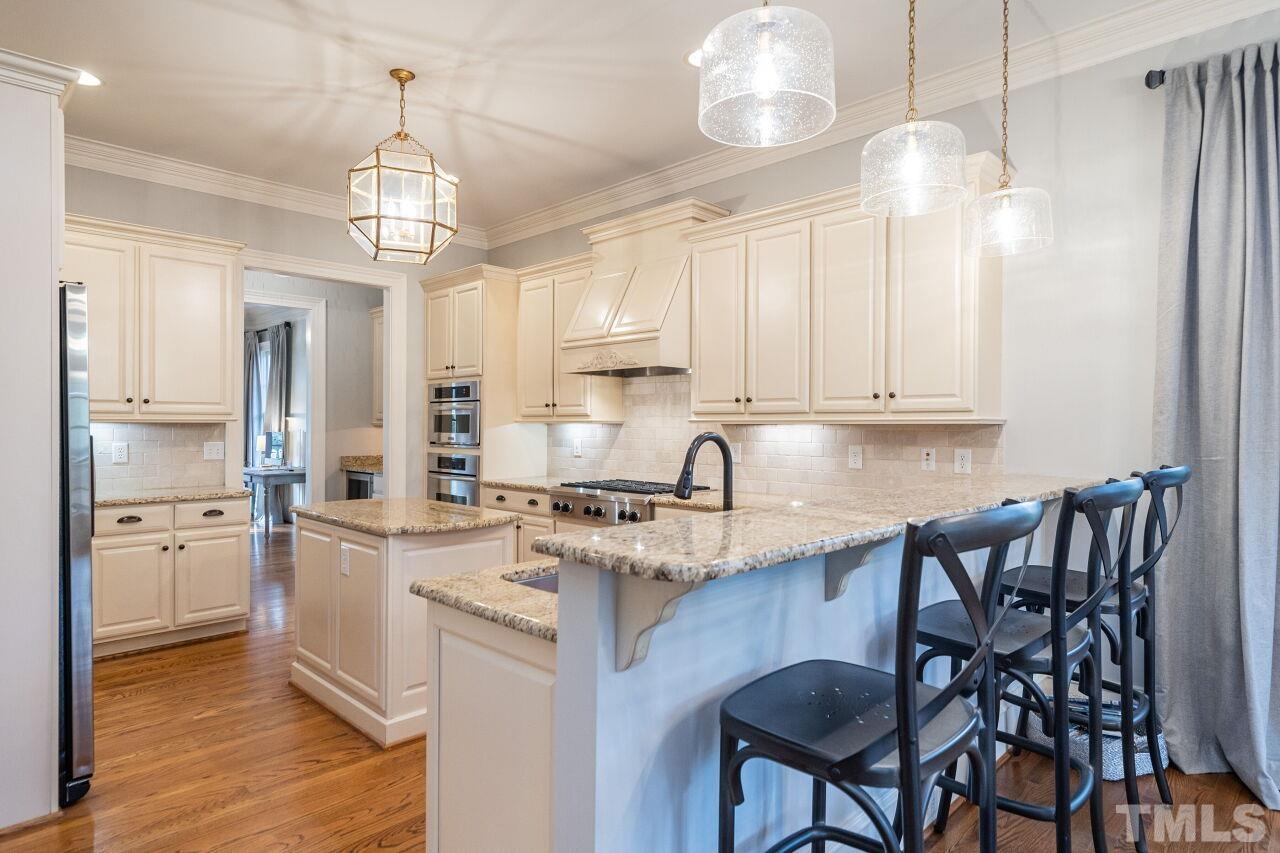 3056 Lewis Farm Road Raleigh, NC 27607 - Photo 14 of 43 a kitchen with kitchen island granite countertop a sink a center island and cabinets