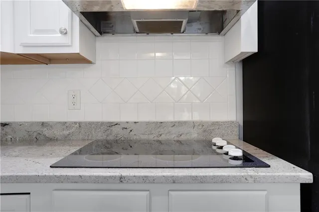 an empty room with chandelier fan and windows