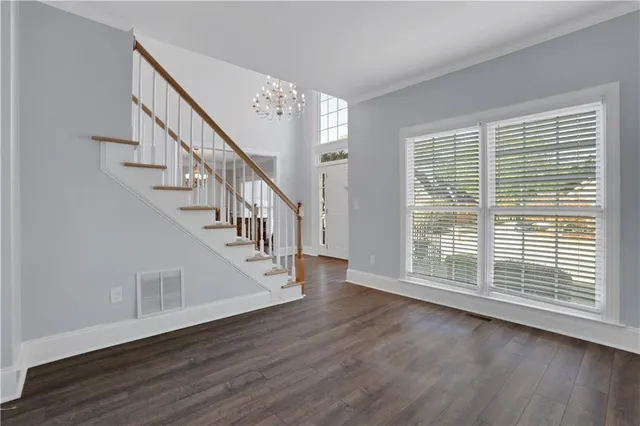 a view of an empty room with wooden floor fireplace and a window