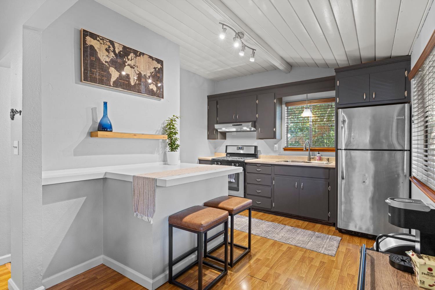 a kitchen with a refrigerator a stove a sink dishwasher and wooden cabinets with wooden floor