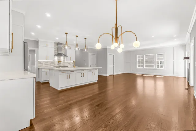 a large white kitchen with wooden floors and glass windows