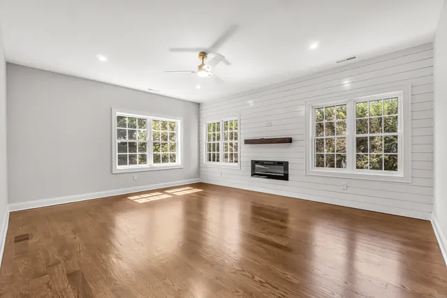 an empty room with wooden floor fireplace and windows