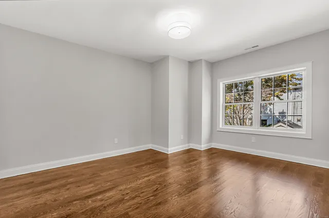a view of a big room with wooden floor and windows