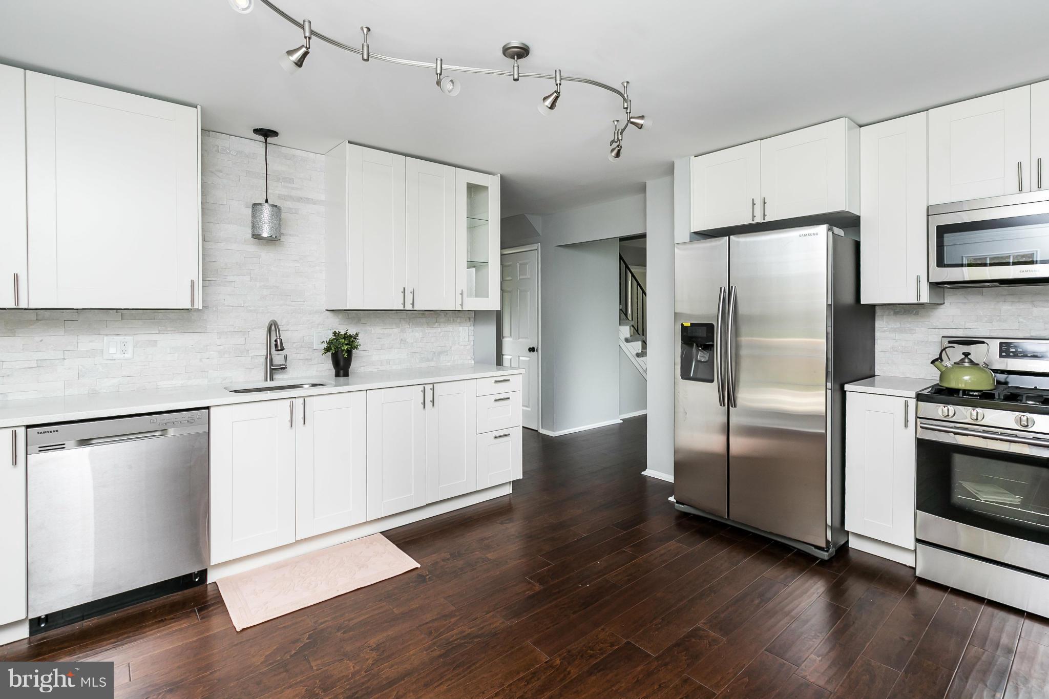 4527 Tapscott Road Baltimore, MD 21208 - Photo 12 of 30 a kitchen with stainless steel appliances white cabinets and wooden floor