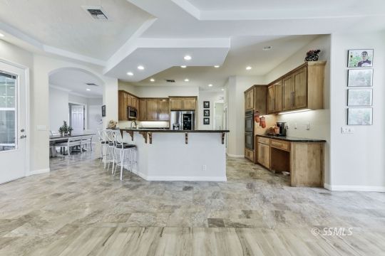 1213 Carolyn Street Ridgecrest, CA 93555 - Photo 10 of 50 a kitchen with stainless steel appliances kitchen island granite countertop a stove top oven a sink a dining table and chairs