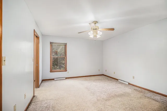 an empty room with windows and chandelier fan