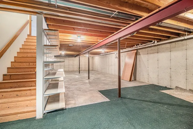 a view of an empty room with wooden floor and staircase