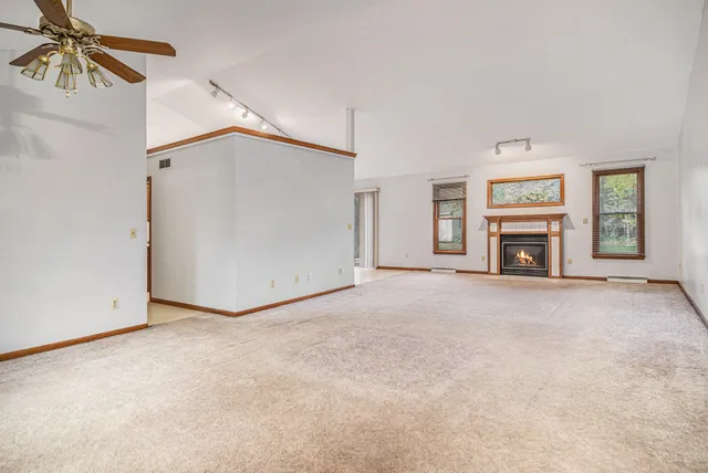 an empty room with windows and fireplace