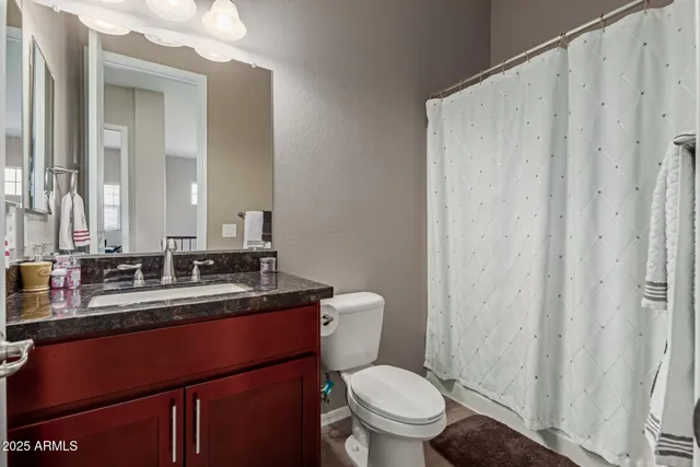 a bathroom with a granite countertop sink toilet and mirror
