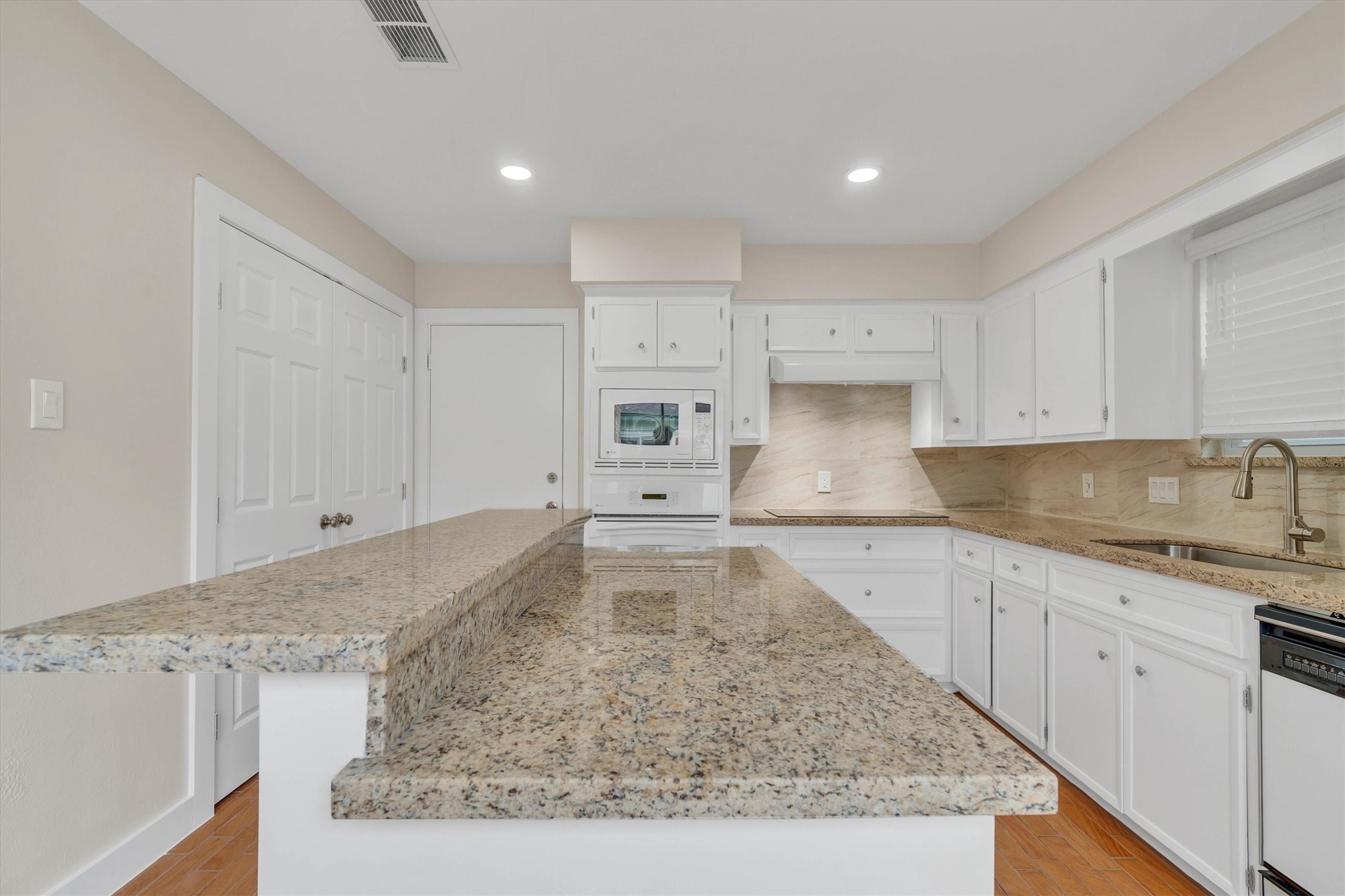 2163 Paso Rello Drive Houston, TX 77077 - Photo 14 of 45 The kitchen features sleek granite countertops, ample white cabinetry, and built-in appliances. The space is well-lit with recessed lighting and has a neutral color palette, creating a clean and inviting atmosphere.