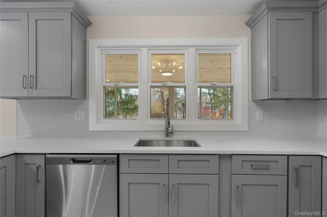 a kitchen with stainless steel appliances granite countertop white cabinets and a window