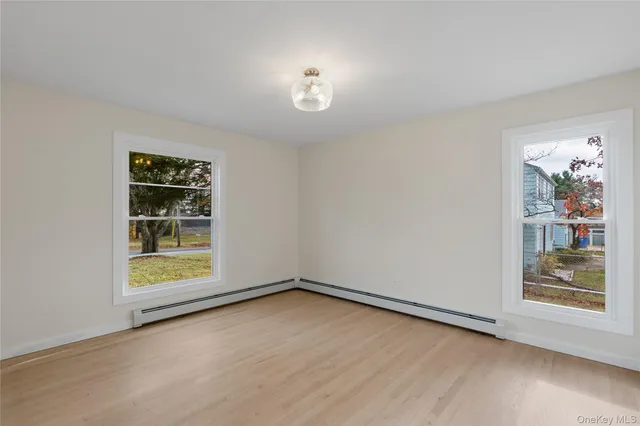 a view of an empty room with a window and wooden floor
