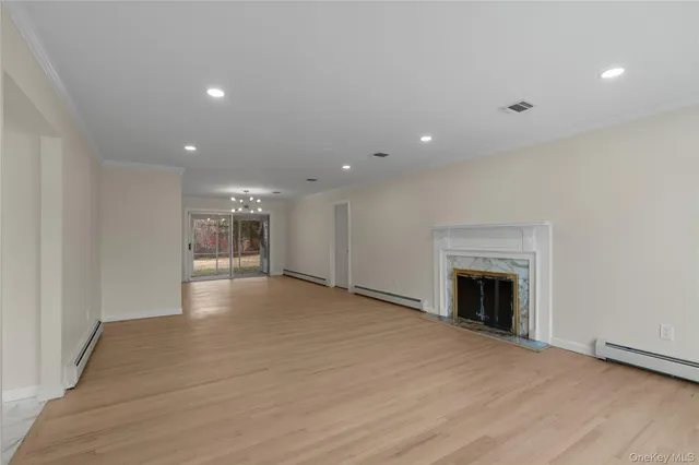 a view of an empty room with wooden floor fireplace and a window