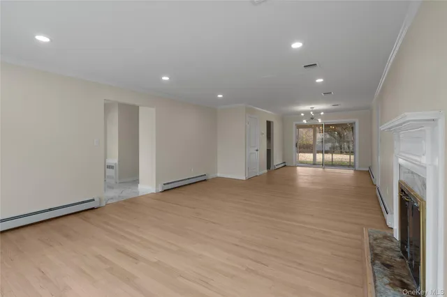 a view of an empty room with wooden floor and a fireplace