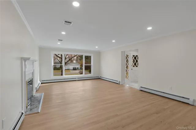 a view of an empty room with a window and wooden floor