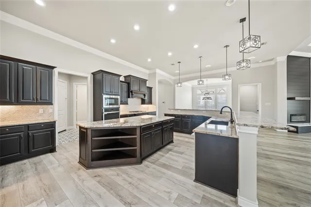 a large kitchen with stainless steel appliances a stove a sink dishwasher a refrigerator and a fireplace with wooden floor